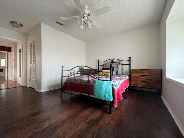bedroom with visible vents, baseboards, a textured ceiling, and wood finished floors
