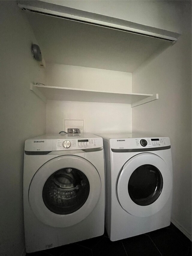 laundry room featuring dark tile patterned flooring, laundry area, and washer and clothes dryer