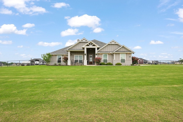 craftsman-style house with board and batten siding, fence, and a front lawn
