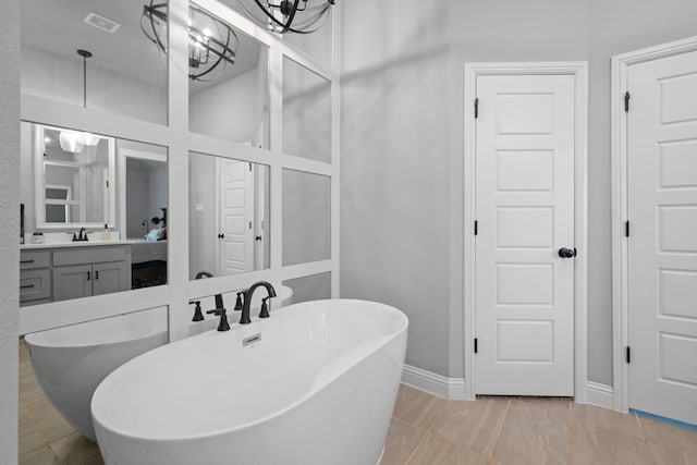 bathroom with baseboards, a freestanding bath, visible vents, and vanity