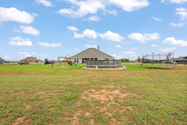 view of yard featuring a playground, a trampoline, and an outdoor pool