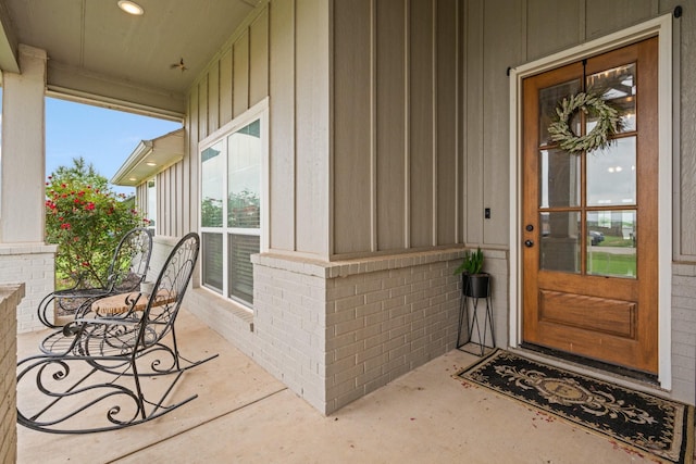 entrance to property with brick siding, board and batten siding, and covered porch