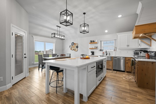 kitchen with open shelves, appliances with stainless steel finishes, a sink, and light wood-style floors