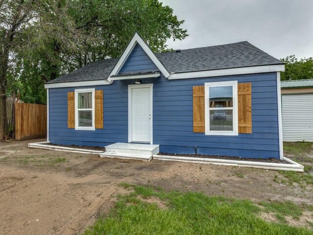 bungalow with a shingled roof and fence