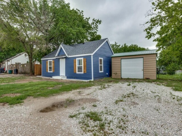 view of front of property with an outdoor structure, fence, driveway, and a detached garage