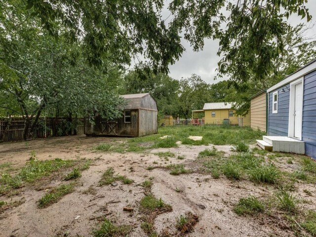 view of yard featuring a storage unit, an outdoor structure, and fence