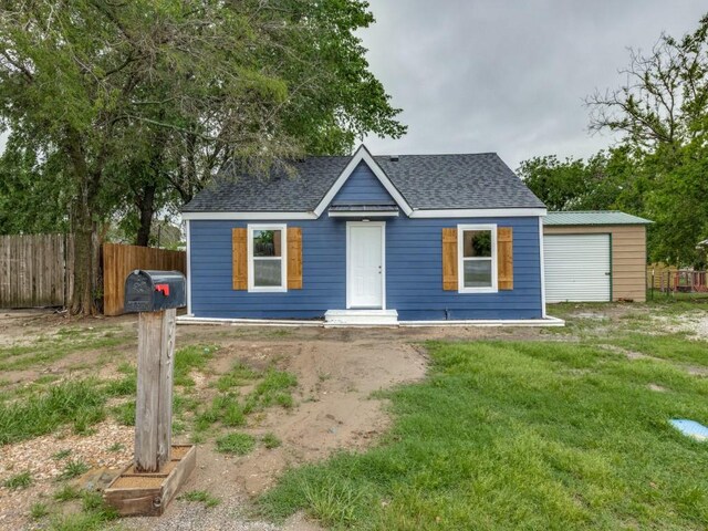bungalow featuring fence, a front lawn, and roof with shingles