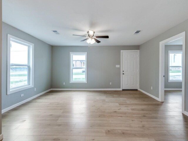 spare room featuring a ceiling fan, visible vents, and a healthy amount of sunlight