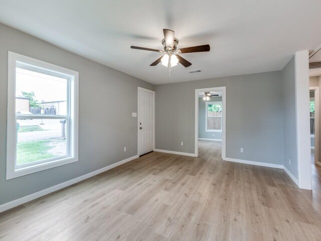 empty room featuring a ceiling fan, baseboards, visible vents, and light wood-style floors