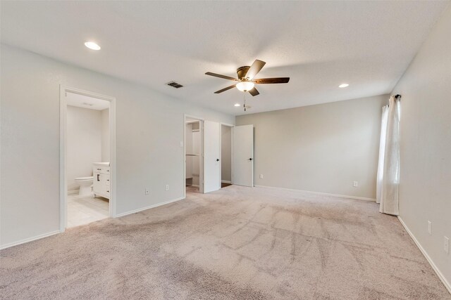 unfurnished bedroom with ensuite bath, visible vents, a spacious closet, light carpet, and recessed lighting