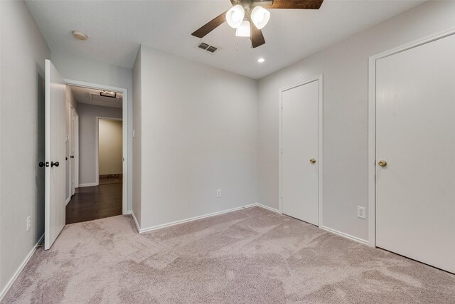 unfurnished bedroom with ceiling fan, attic access, carpet, baseboards, and visible vents