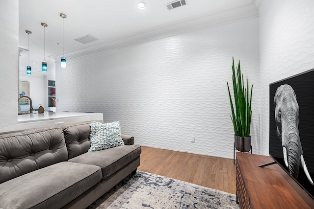 living area featuring visible vents, crown molding, and wood finished floors