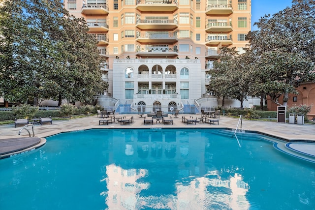 community pool with a patio area and fence