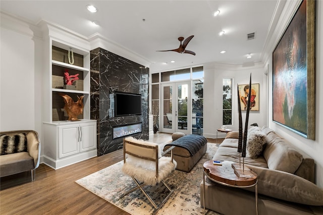 living room featuring visible vents, ornamental molding, ceiling fan, and wood finished floors