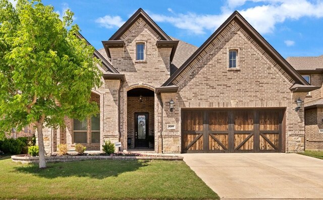 french country home featuring brick siding, driveway, and a front lawn