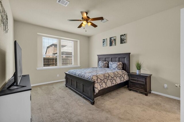 bedroom with baseboards, visible vents, and light carpet