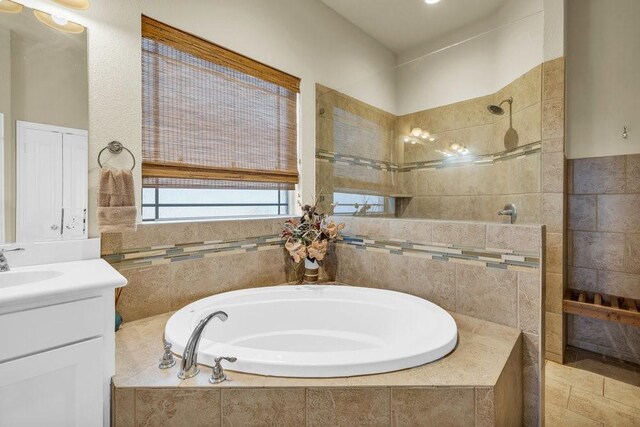 full bathroom featuring tile walls, walk in shower, a bath, and vanity