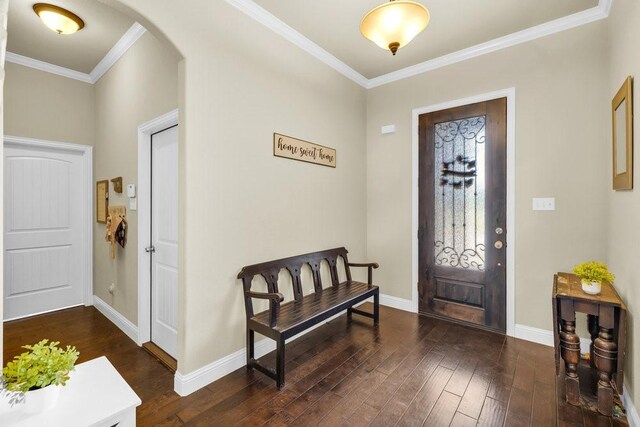 foyer featuring crown molding, baseboards, arched walkways, and dark wood-type flooring