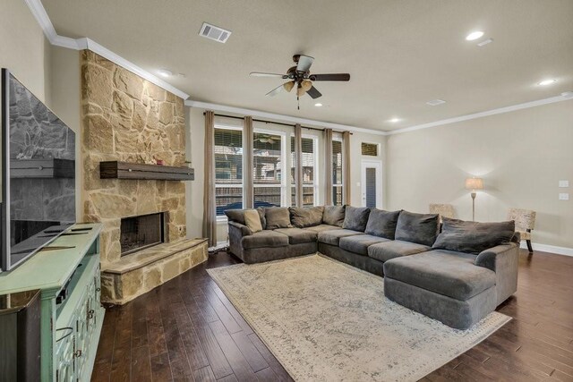 living area featuring visible vents, a ceiling fan, crown molding, and a stone fireplace