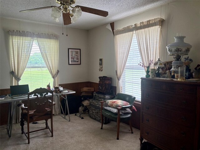 office area with plenty of natural light, a ceiling fan, wainscoting, and a textured ceiling