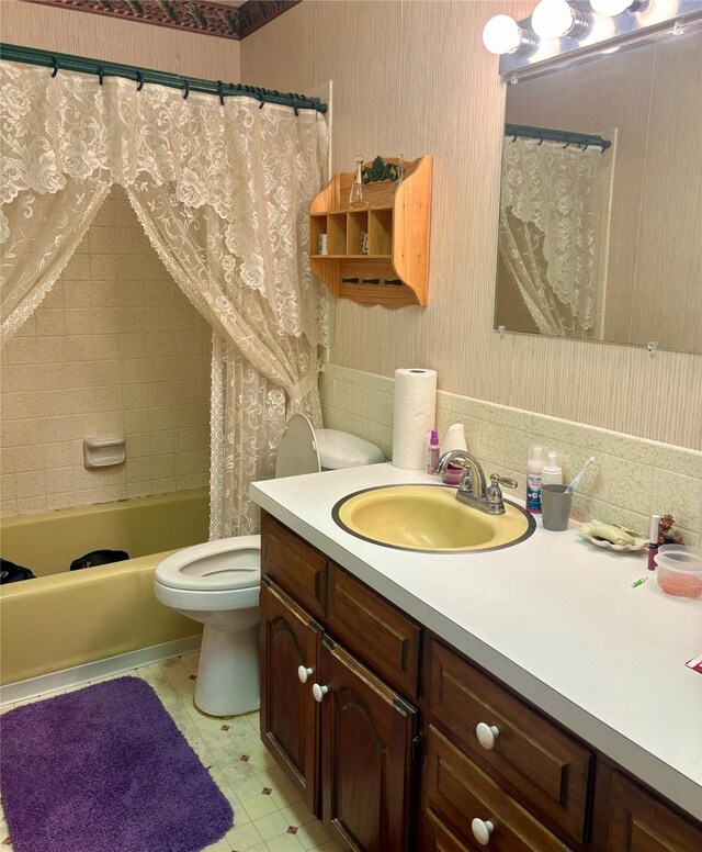 bathroom with vanity, shower / bath combo, toilet, and wallpapered walls