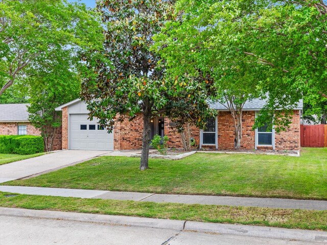 obstructed view of property featuring driveway, a front yard, a garage, brick siding, and fence