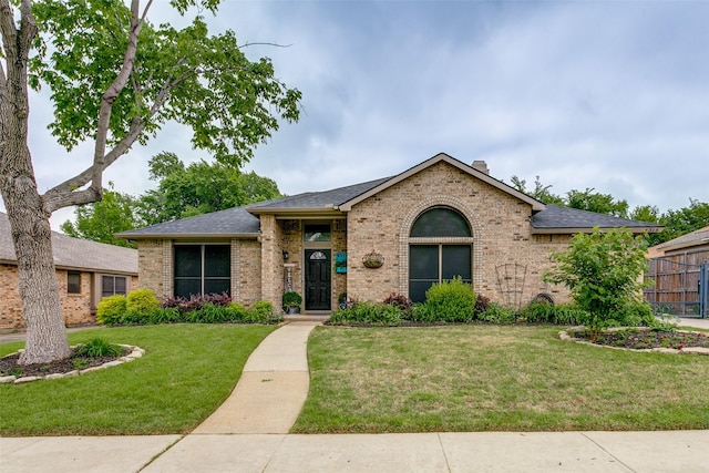 ranch-style home with brick siding, a shingled roof, and a front lawn