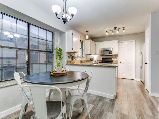 dining space with baseboards, a notable chandelier, and light wood-style flooring