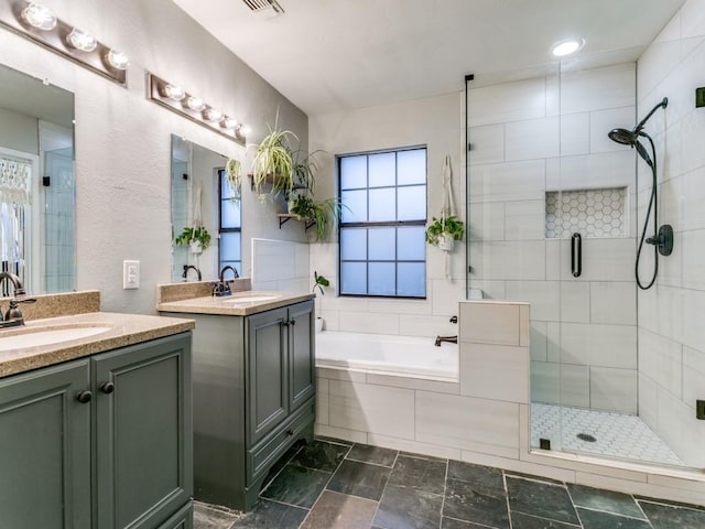 full bath with a sink, a shower stall, a garden tub, and two vanities