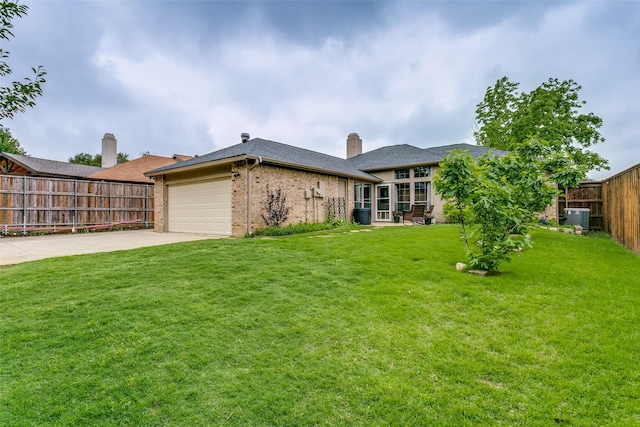 exterior space with fence, an attached garage, cooling unit, a lawn, and driveway