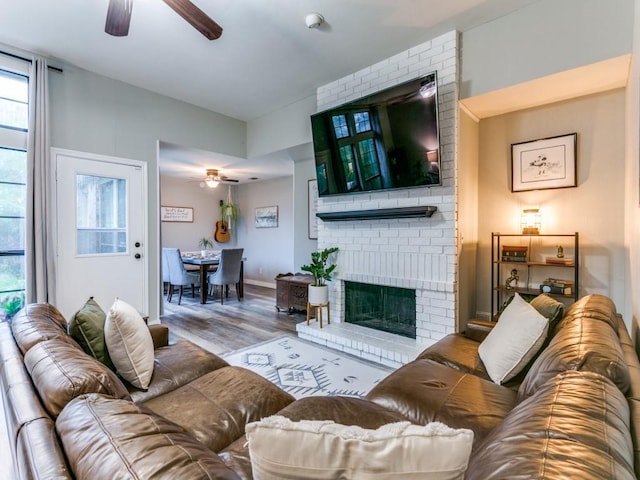living room featuring baseboards, ceiling fan, a fireplace, and wood finished floors