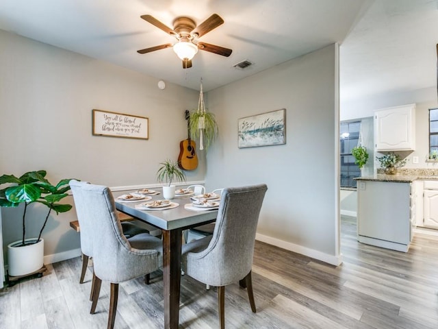 dining room with baseboards, ceiling fan, light wood-type flooring, and visible vents
