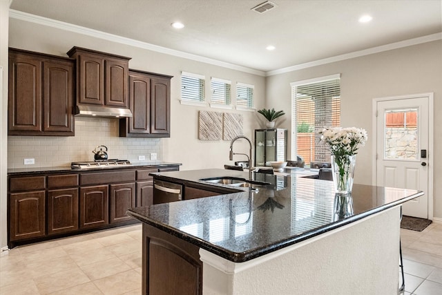 kitchen featuring decorative backsplash, visible vents, a large island with sink, a sink, and under cabinet range hood