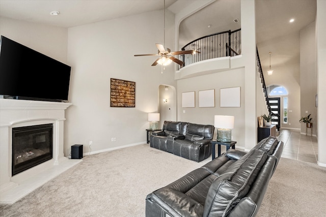 living area with a ceiling fan, carpet, a glass covered fireplace, and high vaulted ceiling