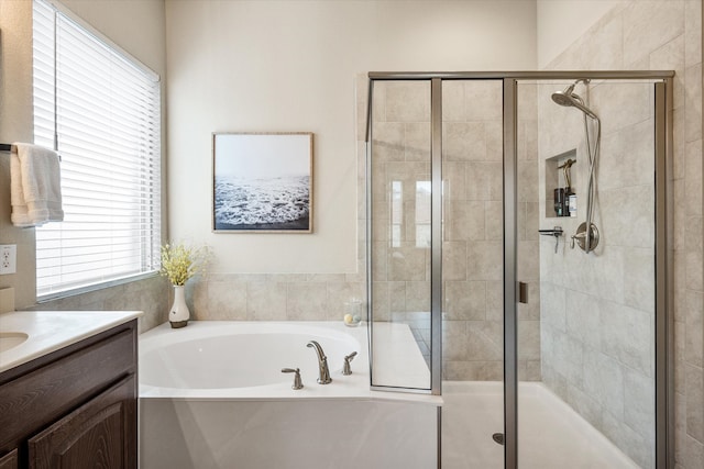 bathroom featuring a garden tub, vanity, and a shower stall
