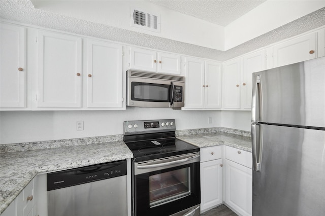 kitchen with white cabinetry, a textured ceiling, appliances with stainless steel finishes, and visible vents