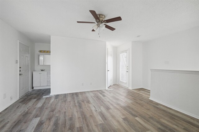 unfurnished living room featuring baseboards, a textured ceiling, ceiling fan, and wood finished floors