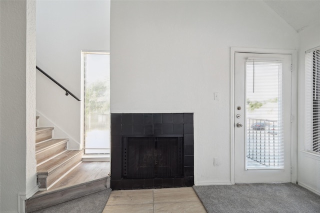 living room with vaulted ceiling, a fireplace, and stairway