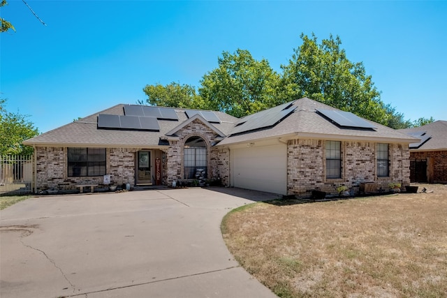 french country inspired facade with brick siding, an attached garage, driveway, and solar panels