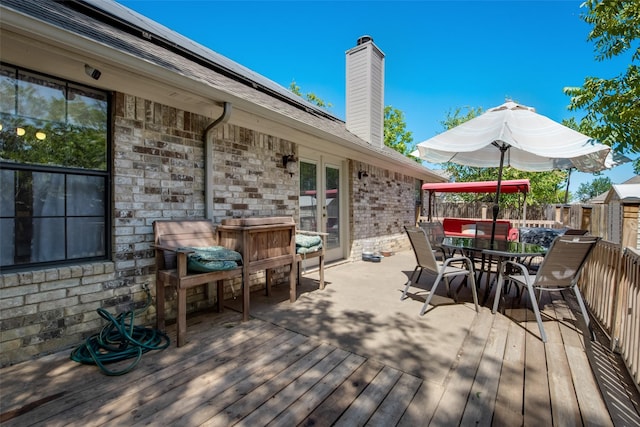 wooden deck with french doors, outdoor dining area, and a fenced backyard