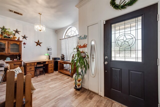 entryway with visible vents, light wood-style flooring, crown molding, and an inviting chandelier