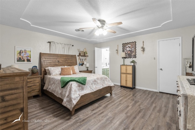 bedroom featuring a textured ceiling, baseboards, wood finished floors, and ensuite bath