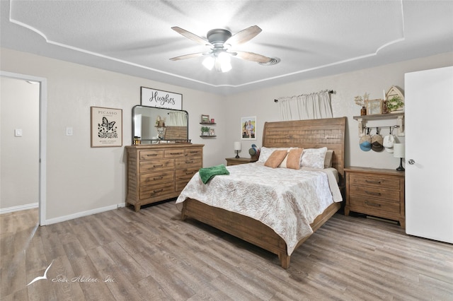 bedroom with baseboards, a textured ceiling, ceiling fan, and wood finished floors