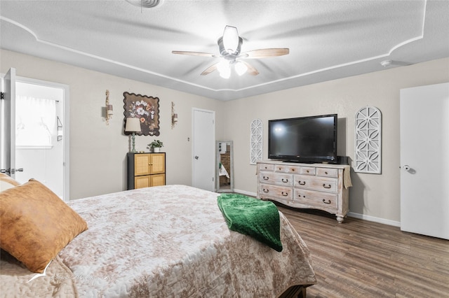 bedroom featuring baseboards, a ceiling fan, a textured ceiling, and wood finished floors