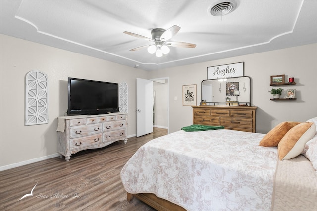 bedroom with visible vents, a ceiling fan, baseboards, and wood finished floors