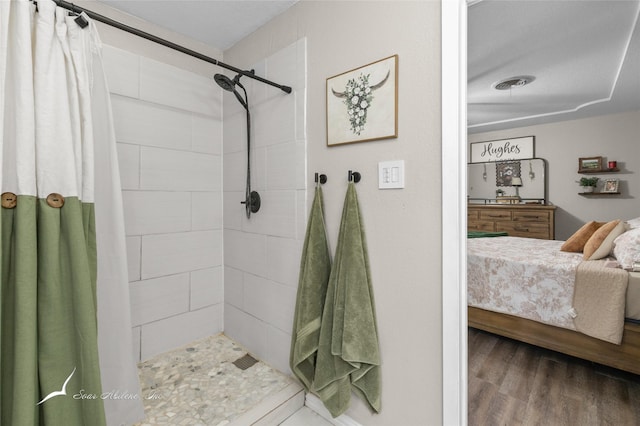 ensuite bathroom featuring connected bathroom, wood finished floors, and tiled shower