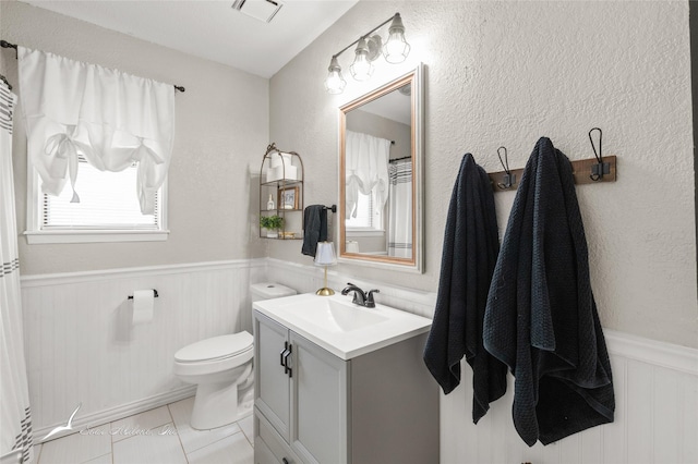 bathroom featuring plenty of natural light, wainscoting, toilet, and vanity