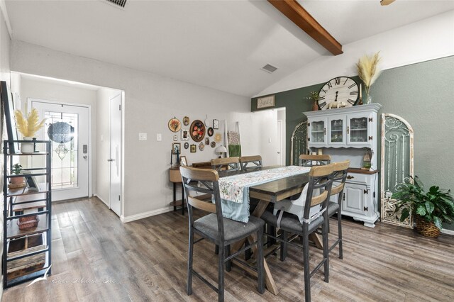 dining space with baseboards, visible vents, vaulted ceiling with beams, and wood finished floors