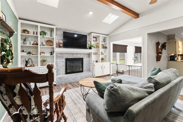 living room with light wood-style floors, vaulted ceiling with skylight, and a fireplace