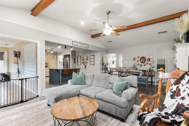 living area with visible vents, lofted ceiling with beams, light wood-style floors, and ceiling fan